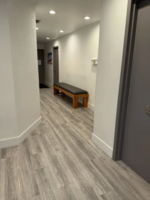 A bright hallway with wood-look flooring and a bench