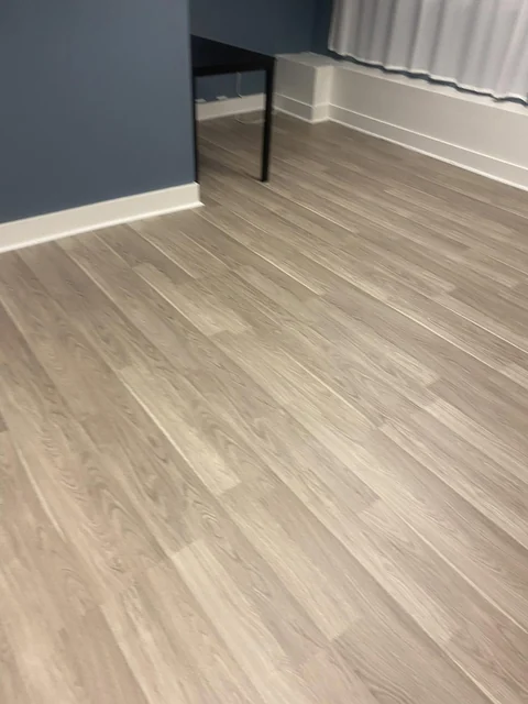 Clean wood-look flooring along the edge of a blue-walled room