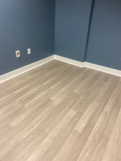 A blue-walled room with clean baseboards and light wood-look flooring