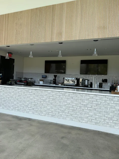 A spacious coffee counter with white tile and dark cabinetry