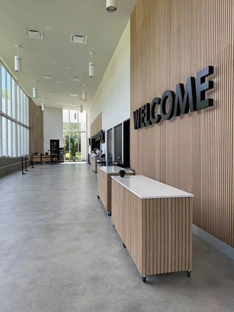 A long light-filled lobby with a welcome desk and tall windows