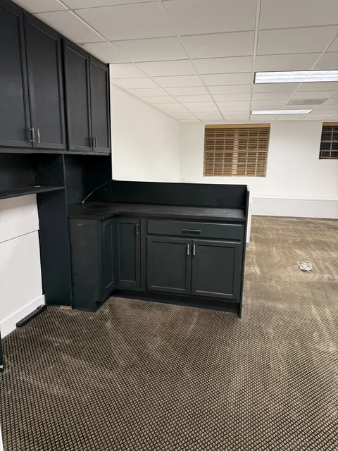 Dark kitchenette cabinets and counters in a customer workspace