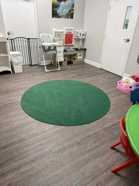 A children’s activity room with a green rug and wood-look floor