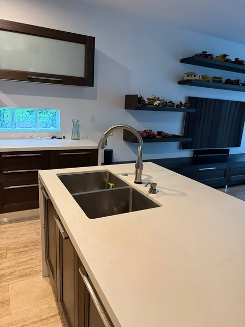 A bright kitchen island with a sink and dark lower cabinets