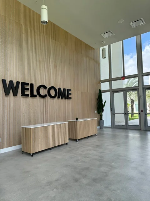 A tall reception space with a welcome sign and wood wall