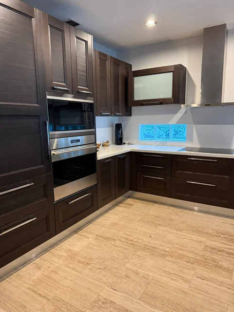 A residential kitchen with dark cabinets and a stainless steel oven